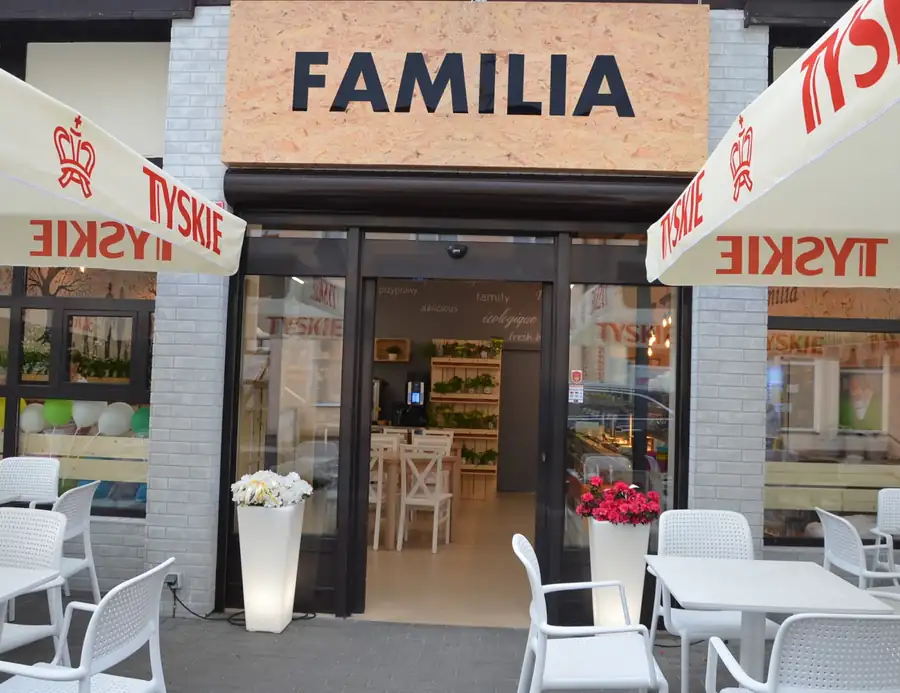 Wejście do restauracji Familia ze stolikami i parasolami przed lokalem