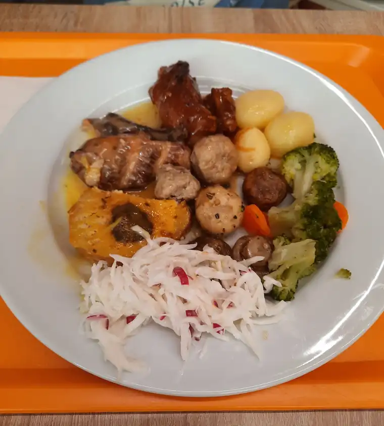 Talerz z mięsem, ziemniakami, kukurydzą, brokułem i surówką na pomarańczowej tacy